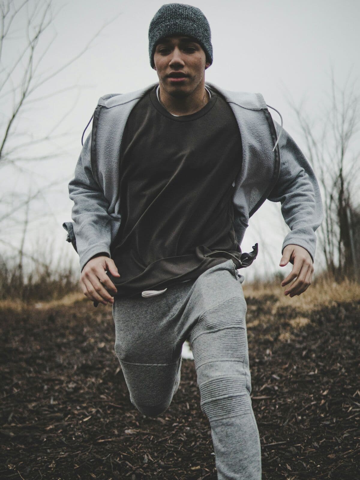 Runner in grey joggers and hoodie mid-stride outdoors